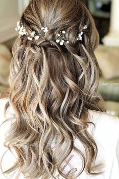 the back of a woman's head with long wavy hair and flowers in her hair