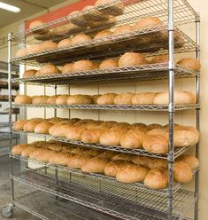 a rack filled with lots of bread on top of metal shelves in a bakery shop