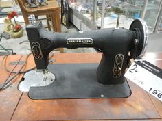 an old black sewing machine sitting on top of a wooden table