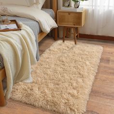 a bed room with a neatly made bed and a rug on the floor