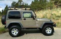 the jeep is parked on the side of the road in front of some grass and trees