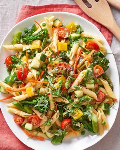 a white plate topped with pasta and veggies on top of a red cloth