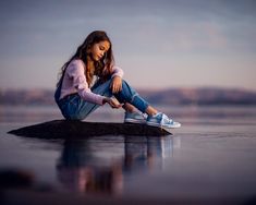 a woman sitting on top of a rock in the water