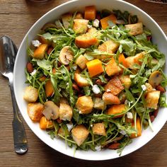 a salad with croutons and cheese in a white bowl