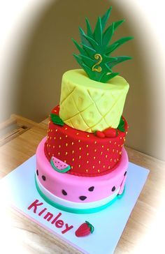 a three tiered cake with a pineapple on top and strawberries on the bottom