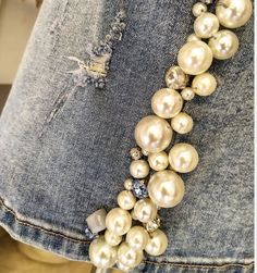 a necklace made out of pearls and crystal stones on a pair of jean pants,