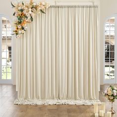 a living room with white curtains and flowers on the window sill next to candles