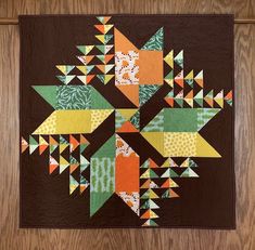 a quilted wall hanging on the side of a wooden door with an abstract design