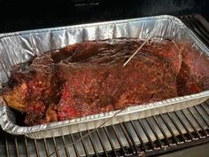 a roasting pan with meat on it sitting on an open grill door, ready to be cooked