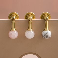 three marble knobs mounted to the side of a wall with gold handles and brass fittings