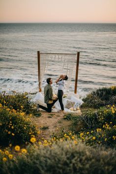 a man and woman sitting on top of a beach next to the ocean