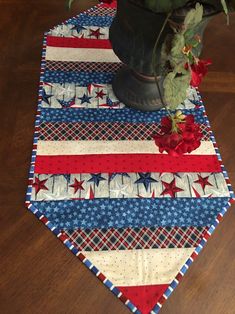 a potted plant sitting on top of a wooden table covered in red, white and blue fabric