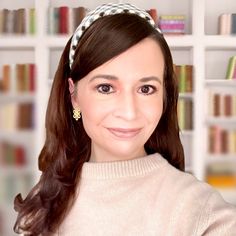 a woman with long hair wearing a headband in front of a bookshelf