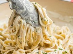 a fork full of pasta with sauce and parmesan cheese on the top, in a bowl