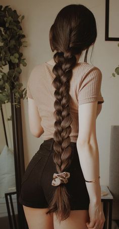 a woman with very long hair standing in front of a mirror wearing high waist shorts