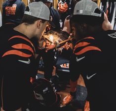 two football players are looking at something on the floor