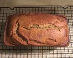 a loaf of banana bread sitting on top of a cooling rack next to a knife