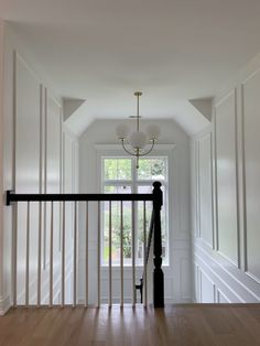 an empty room with white walls and wood floors, along with a black banister