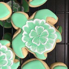 cookies decorated with green and white icing on a cooling rack in the shape of flowers