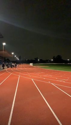 an empty tennis court at night with people on it