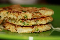 three crab cakes stacked on top of each other in a green plate with a fork