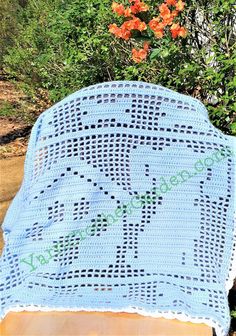 a blue crocheted blanket sitting on top of a wooden table next to flowers