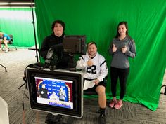 three people are sitting in front of a green screen and giving the thumbs up sign