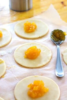 small tortillas with orange marmalade toppings and a spoon on the table