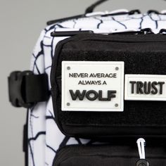 a black and white backpack with two tags on the front that says never average, always a wolf