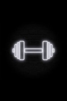 two dumbbells glowing in the dark on a brick wall with light coming from them