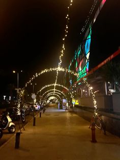 a street with lights and motorcycles parked on the side of it at night in front of a building