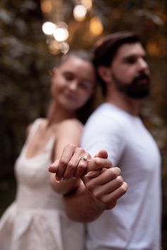 a man and woman are holding hands in front of the camera with their fingers together