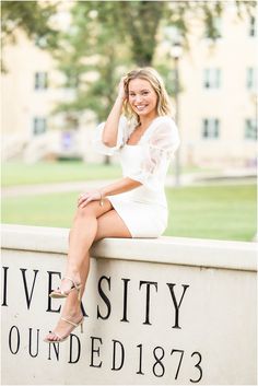 a beautiful woman sitting on top of a sign