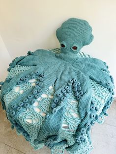 an octopus is sitting on the floor with a blue knitted blanket over it's head