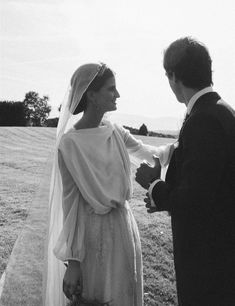 a man and woman dressed in wedding attire standing next to each other on the grass