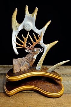 an antelope sculpture sitting on top of a wooden table next to another deer's head