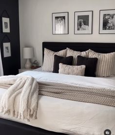 a bed with white sheets and pillows in a bedroom next to pictures on the wall