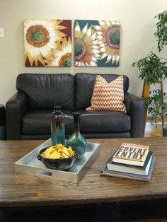 a living room with a couch, coffee table and two paintings