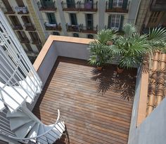 a balcony with potted plants on the floor and a white chair next to it