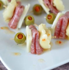 small appetizers with olives and cheese on a white plate