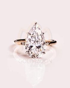 a pear shaped diamond ring on a white surface