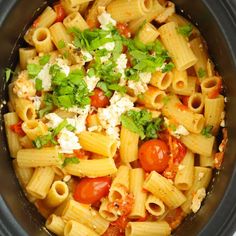 a crock pot filled with pasta, tomatoes and fettuccine topped with parsley