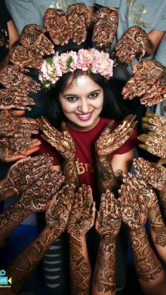 a woman with her hands covered in hendi and flowers on top of her head