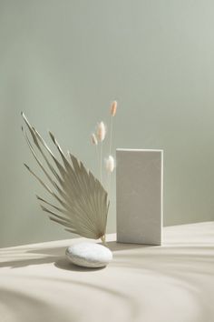 a white vase sitting next to a small square object on top of a table covered in sand