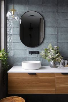 a bathroom sink with a mirror above it and a plant in the corner next to it