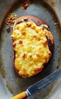 a cheese covered sandwich on a plate with a knife