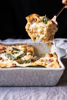 a person holding a spoon full of lasagna casserole with spinach and cheese