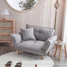 a living room with a round mirror and grey couch in front of a white rug