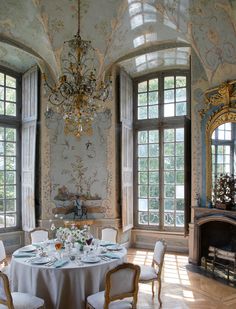 an elegant dining room with chandelier and table set for four in front of large windows