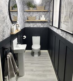 a white toilet sitting in a bathroom next to a sink under a mirror and towel rack